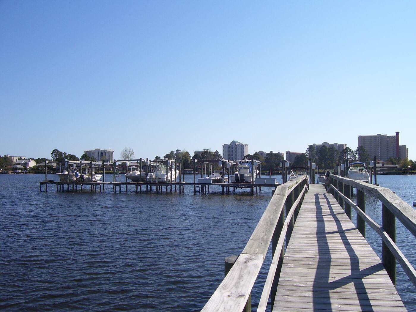 A dock out over Grand Lagoon, with boat lifts and the east-end skyline beyond